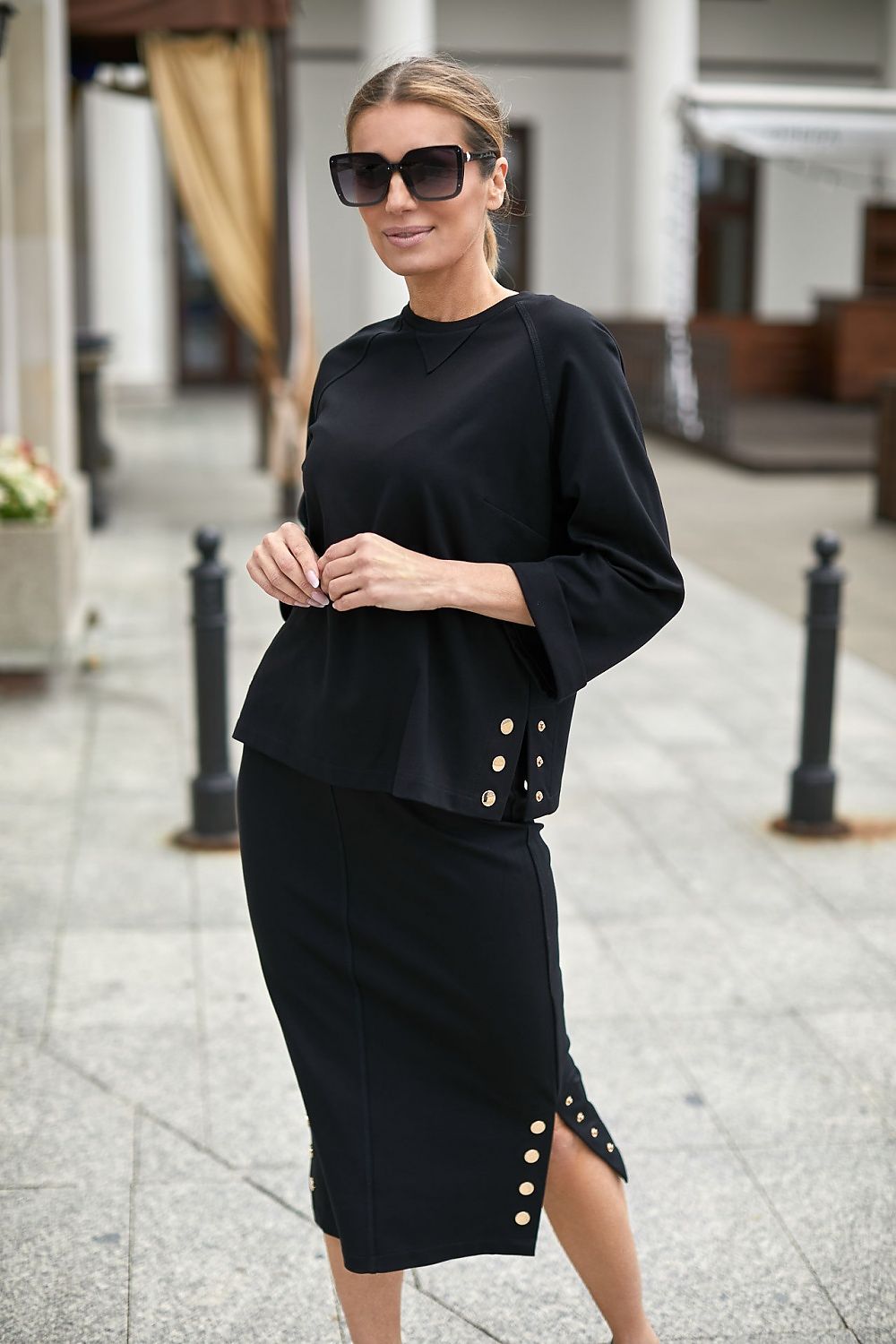 Jupe noire midi fendue avec boutons dorés pour un look élégant et moderne, parfaite pour le travail ou une soirée.