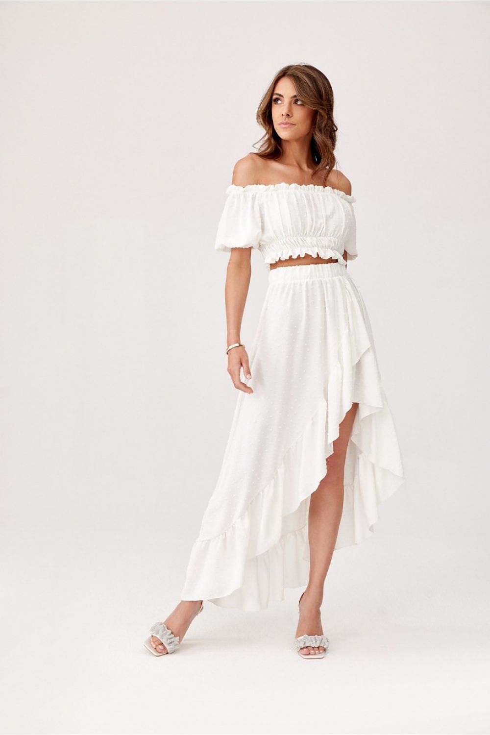 Jupe blanche asymétrique midi avec détails volants pour un look élégant et estival, parfaite pour une sortie chic.